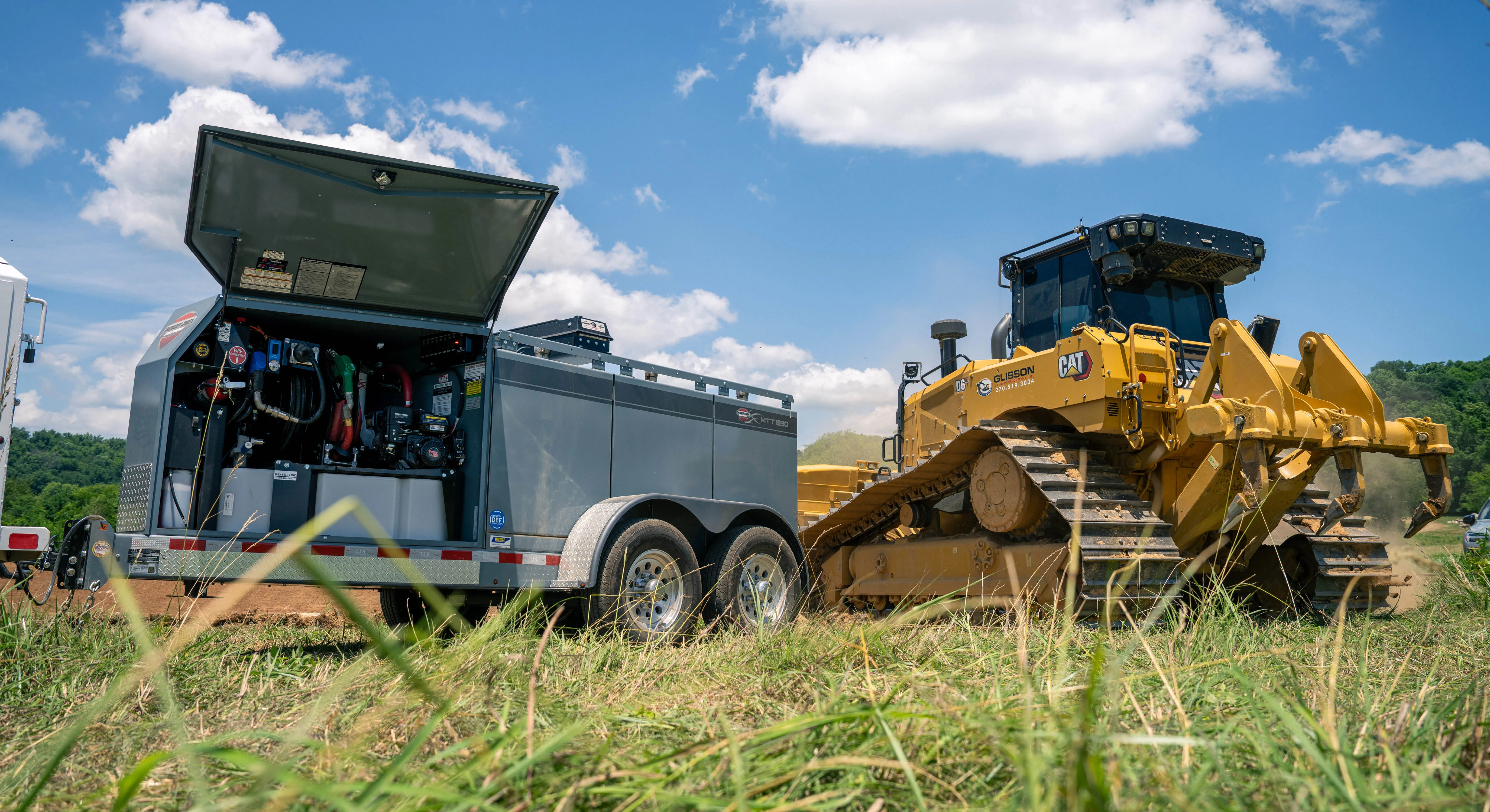 Thunder Creek Equipment MTT690 fuel and service trailer with its service compartment open, parked beside a Glisson Land Development branded CAT D6 dozer on a jobsite.
